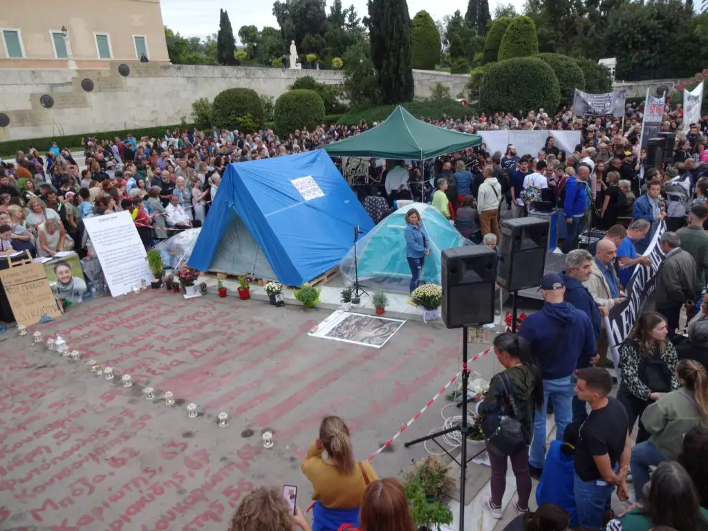 Unser Foto zeigt das Zelt des hungerstreikenden Panos Routsis vor dem Parlament in Athen. Es ist umgeben von Personen, die sich mit ihm solidarisch verhalten. 