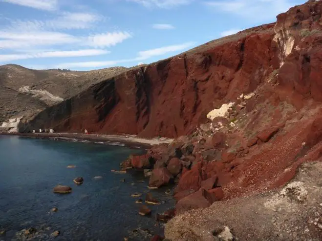 Im Schatten der hochaufragenden roten Felsen trauen sich ein paar der Touristen unerschrocken ins Wasser. 