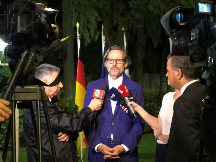 Unser Foto (© Griechenland Zeitung / Yeliz K.) zeigt den deutschen Botschafter Jens Plötner bei der Feier zum Tag der deutschen Einheit im Garten seiner Residenz, als er den Journalisten Rede und Antwort stand.
