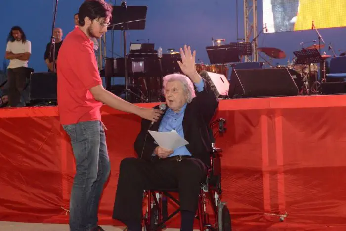 Unser Archivfoto (© Eurokinissi) zeigt Mikis Theodorakis während eines Konzerts anlässlich des 90. Jubiläums der Kommunistischen Partei Griechenlands (KKE) Anfang Juni 2015 im „Theatro Petras“ in Petroupoli – westlich von Athen.