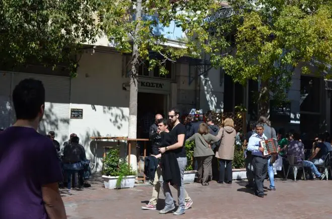 Unser Foto (© Jan Hübel / Griechenland Zeitung) entstand vor dem bekannten Souvlaki-Laden „Kosta“ am Agia-Irini-Platz. In diesem winzigen Grillgeschäft, so meinen viele Athener, seien die Souvlakia besonders köstlich. Dafür lohnt sich sogar das Anstellen.