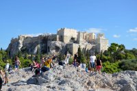 Unser Archivfoto (© Jan Hübel / Griechenland Zeitung) zeigt Touristen auf dem Pnyx-Hügel in Athen; im Hintergrund die Akropolis.