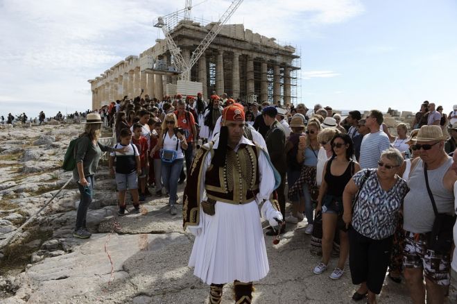 Unser Archivfoto (© Eurokinissi) entstand am 12. Oktober 2016 und zeigt Touristen auf der Athener Akropolis sowie Evzones: Soldaten der griechischen Präsidialgarde. Anlass für ihre Anwesenheit war eine Feierlichkeit anlässlich des Rückzuges der deutschen Besatzer aus Athen im Jahre 1944.