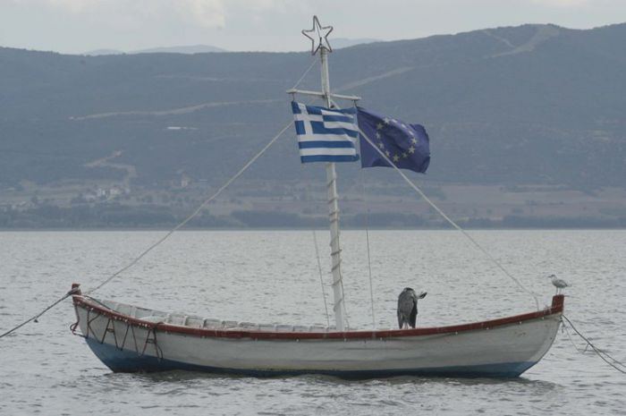 Auf unserem Foto ist ein Kaiki (© Eurokinissi) mit einer griechischen und europäischen Fahne zu sehen. Trotz der Bemühungen der EU, die Boote aus dem Verkehr zu ziehen, hisste der Bootsfahrer auch eine EU-Fahne.