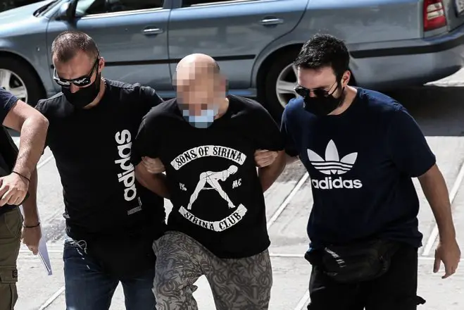 Foto (© Eurokinissi): Der Polizist ließ es sich nicht nehmen, im T-Shirt einer bekannten Pornoproduktion vor den Staatsanwalt zu treten. 