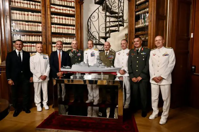 Unser Foto (© griechisches Verteidigungsministerium) zeigt die griechische und die italienische Delegation mit einem Modell der erworbenen Fregatte.