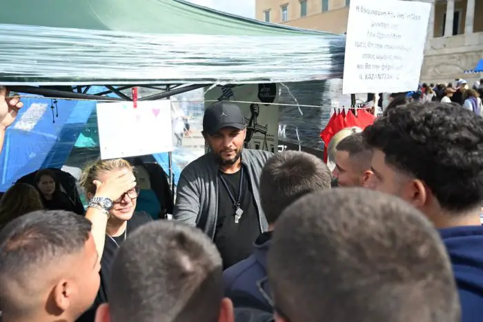 Unser Foto (© Eurokinissi) zeigt Panos Routsis im Gespräch mit Passanten, die ihm gegenüber Solidarität unter Beweis stellen.