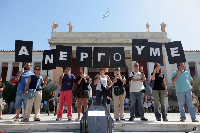 Unser Archivfoto (© Eurokinissi) entstand während einer Demonstration vor dem Athener Parlament im September 2012. Mit einem Wortspiel machten die Beteiligten auf die hohe Arbeitslosigkeit aufmerksam. Auf dem Transparent steht nicht wie üblich „Απεργούμε“ – zu Deutsch: „Wir streiken“ – sondern „Ανεργούμε“, was in etwa „wir sind arbeitslos“ bedeutet.