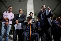 Unser Foto (© Eurokinissi) entstand am Mittwoch vor der Polizeidirektion in Athen. In der Mitte sitzt der Widerstandskämpfer Manolis Glezos. Im Bild rechts steht Panagiotis Lafazanis.