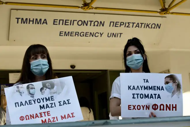 Unser Foto (© Eurokinissi) entstand während einer Demonstration vor einem Krankenhaus in Athen. Auf dem linken Transparent steht: „Wir kämpfen mit euch, ruft mit uns.“ Und auf dem rechten: „Auch die verdeckten Münder haben eine Stimme.“