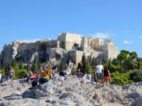 Unser Archivfoto (© Jan Hübel / Griechenland Zeitung) zeigt Touristen auf dem Pnyx-Hügel in Athen; im Hintergrund die Akropolis.