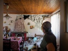 Unser Foto (© Eurokinissi) entstand am Sonntag (7.6.) auf Euböa. Es zeigt eine Frau vor der beschädigten Wand ihres Hauses. Teile des Putzes und Mauersteine waren auf ihr Bett gestürzt.